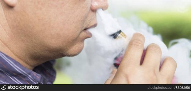 man blowing smoke of electronic cigarette from his mouth and nose