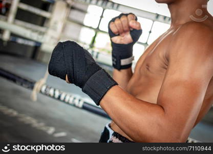 Man boxer wrapping his hand in boxing arena sport.