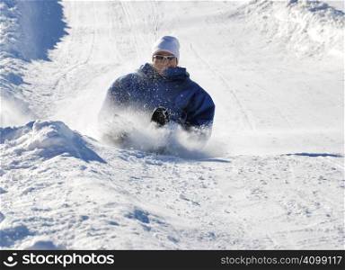 man braking while sledding fast down the hill with snow background