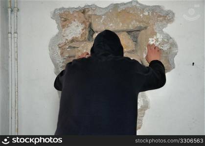 Man breaking down a wall with his bare hands.