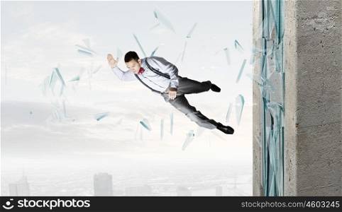 Man breaking through glass. Young determined businessman breaking glass with karate punch