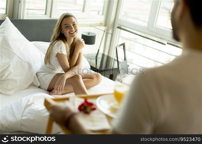 Man bringing breakfast to his woman in bed at home