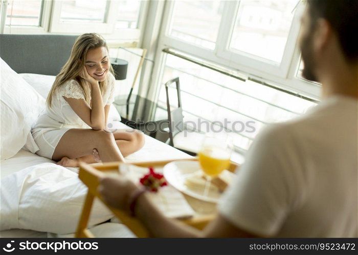 Man bringing breakfast to his woman in bed at home