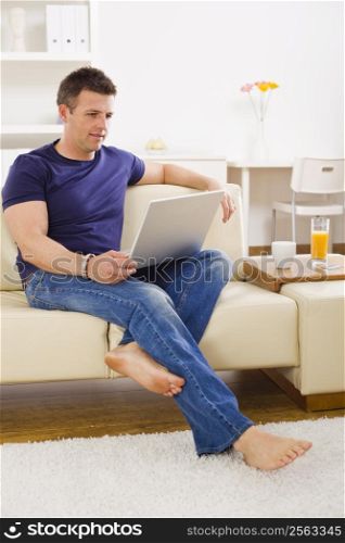 Man browsing internet on laptop computer at home.
