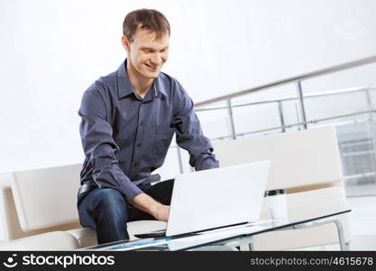 Man browsing web. Young handsome businessman sitting and using laptop