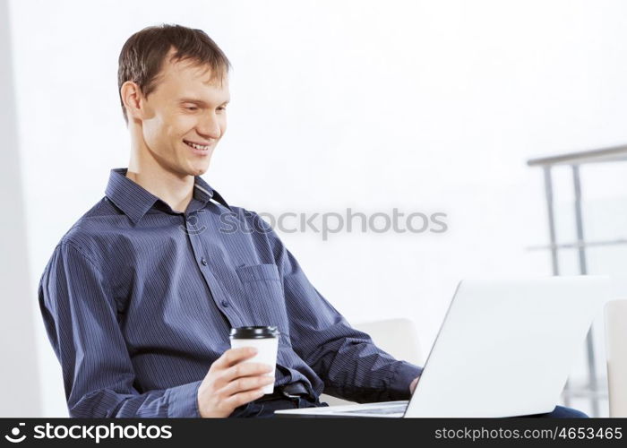 Man browsing web. Young handsome businessman sitting and using laptop