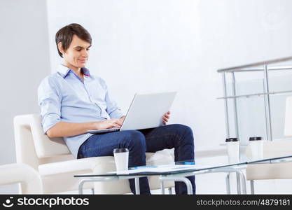 Man browsing web. Young handsome businessman sitting and using laptop