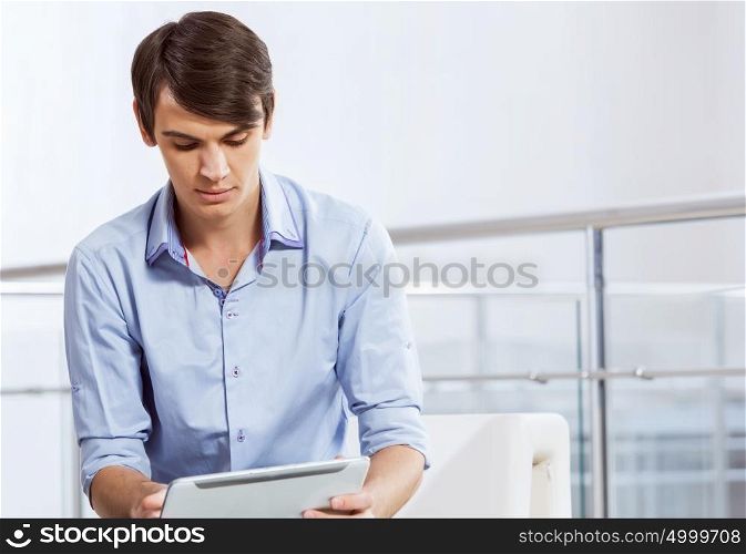 Man browsing web. Young handsome businessman sitting and using tablet pc