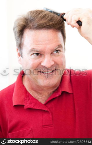 Man brushing his hair in the bathroom mirror.