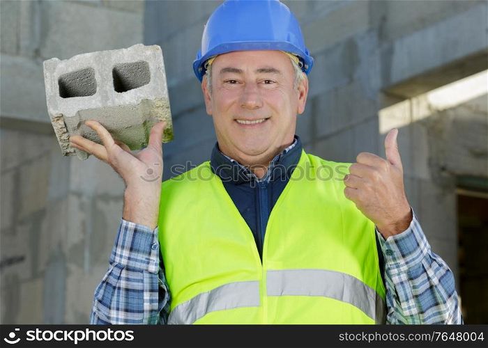 man builder holding a brick outdoors