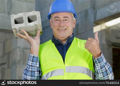 man builder holding a brick outdoors