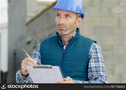 man builder holds a clipboard and pen