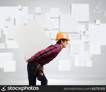 Man builder presenting something. Young smiling craftsman carrying white cube on back