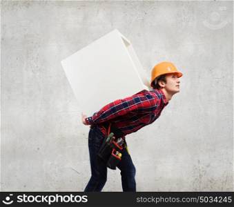Man builder presenting something. Young smiling craftsman carrying white cube on back