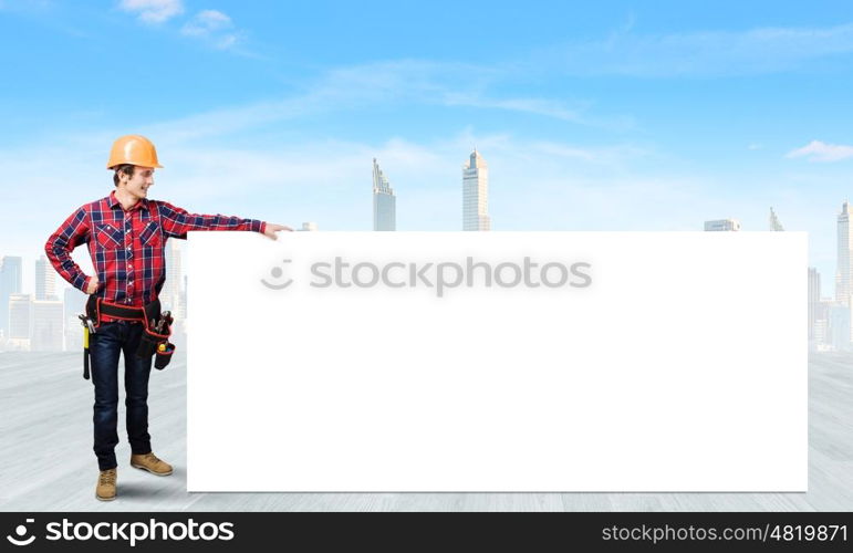 Man builder presenting something. Young smiling craftsman holding with blank banner. Place for text