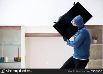 Man burglar stealing tv set from house
