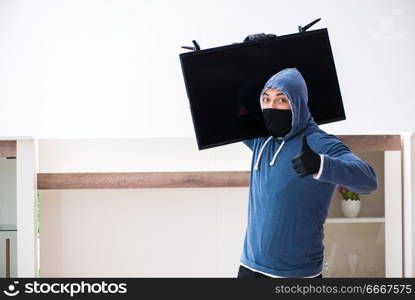 Man burglar stealing tv set from house