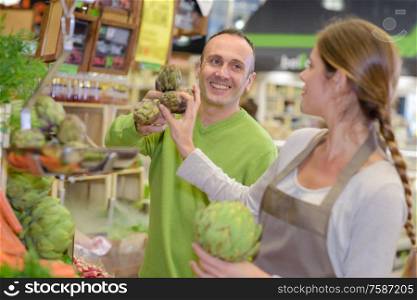 Man buying artichokes in shop