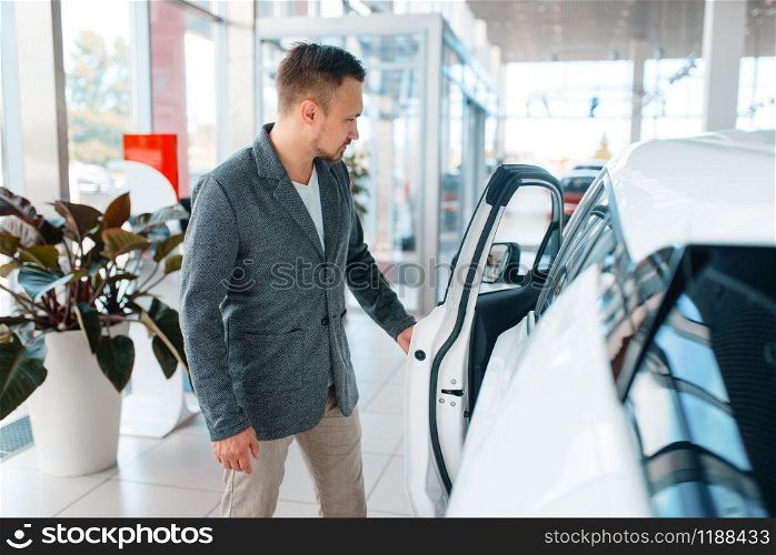 Man buying new car in showroom. Male customer choosing vehicle in dealership, automobile sale, auto purchase