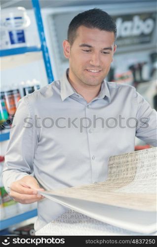 man buying wallpaper at hardware store for do-it-yourself project