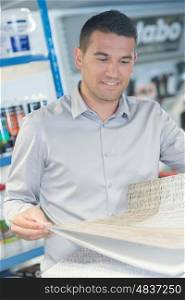 man buying wallpaper at hardware store for do-it-yourself project