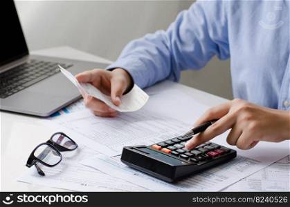 Man calculates bills on home income Use the modern office balance and expense calculator. Businessman making paperwork to pay taxes, expenses, accounting, tax concept.