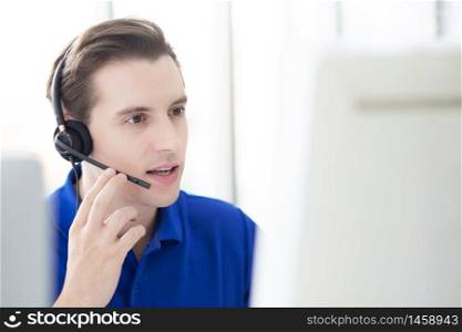 Man call-center agent with headset working on support hotline in the office