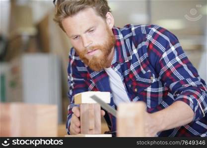 man carpenter using file on piece of wood