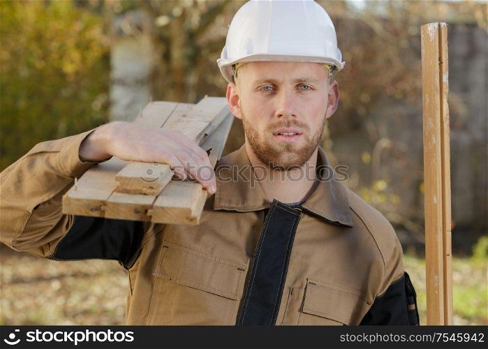 man carries wook to cut at workshop
