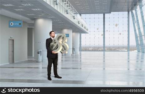 Man carry currency sign. Young businessman in office interior carrying dollar sign