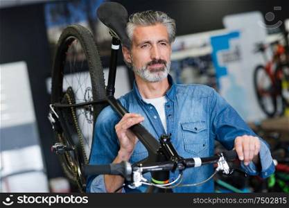 man carrying a bicycle in a shop