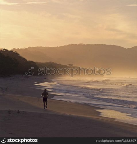 Man carrying a surfboard on coast of Costa Rica