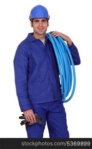 Man carrying coil of piping