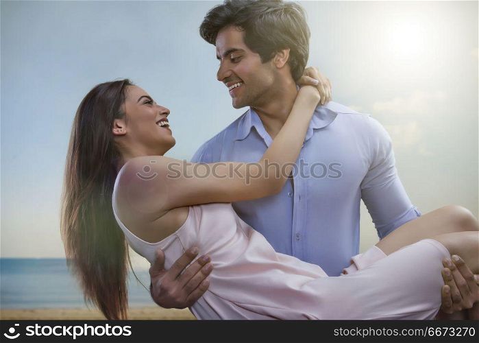 Man carrying girlfriend on beach