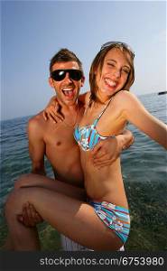 Man carrying his girlfriend at the beach
