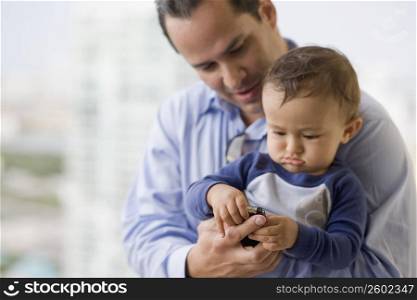 Man carrying his son playing with a mobile phone