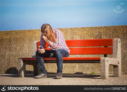 Man casual style sitting on bench outdoor holding cell phone in hand, guy using smartphone
