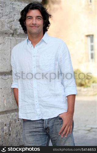 Man casually leaning against stone building