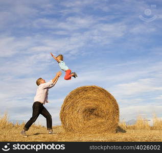 man catching boy jumping from hay bale