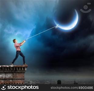 Man catching moon. Young man in casual catching moon with rope