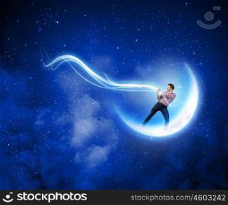 Man catching moon. Young man in casual standing on moon