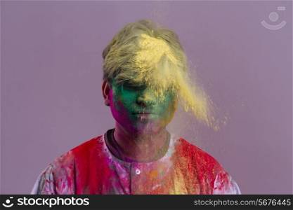 Man celebrating Holi festival with powder paints over colored background