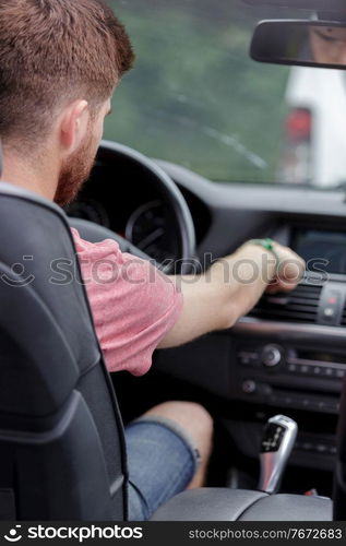 man changing radio station while driving a car