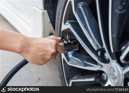 Man checking air pressure and filling air in the tires of car. Concept picture