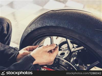 man checking air pressure of motorcycle wheel before traveling