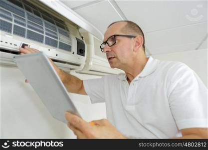man checking airconditioning manual while using it
