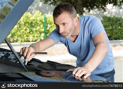 man checking engine of breakdown car