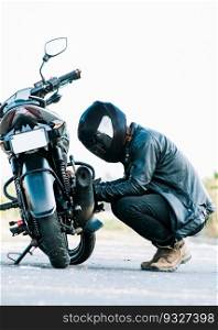 Man checking his motorcycle on the road. Motocyclist fixing the motorcycle on the road, Biker repairing motorcycle on the road