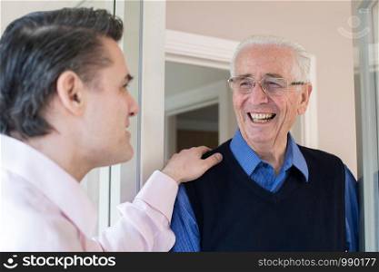 Man Checking On Elderly Female Neighbor