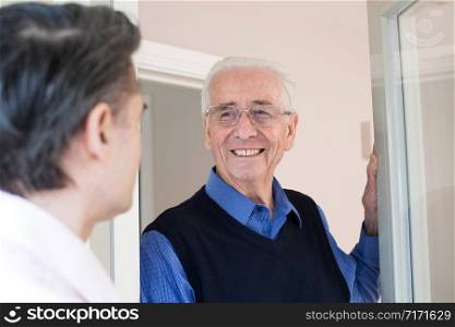 Man Checking On Elderly Male Neighbor